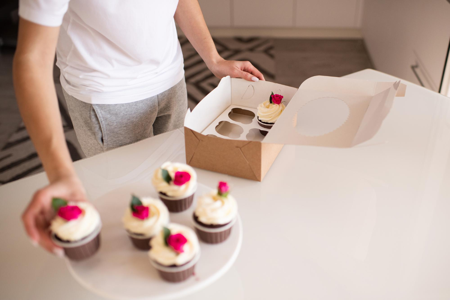 Mężczyzna w białej koszulce wyjmujący muffinki z kartonowego pudełka. Mężczyzna w białej koszulce wyjmujący muffinki z kartonowego pudełka.